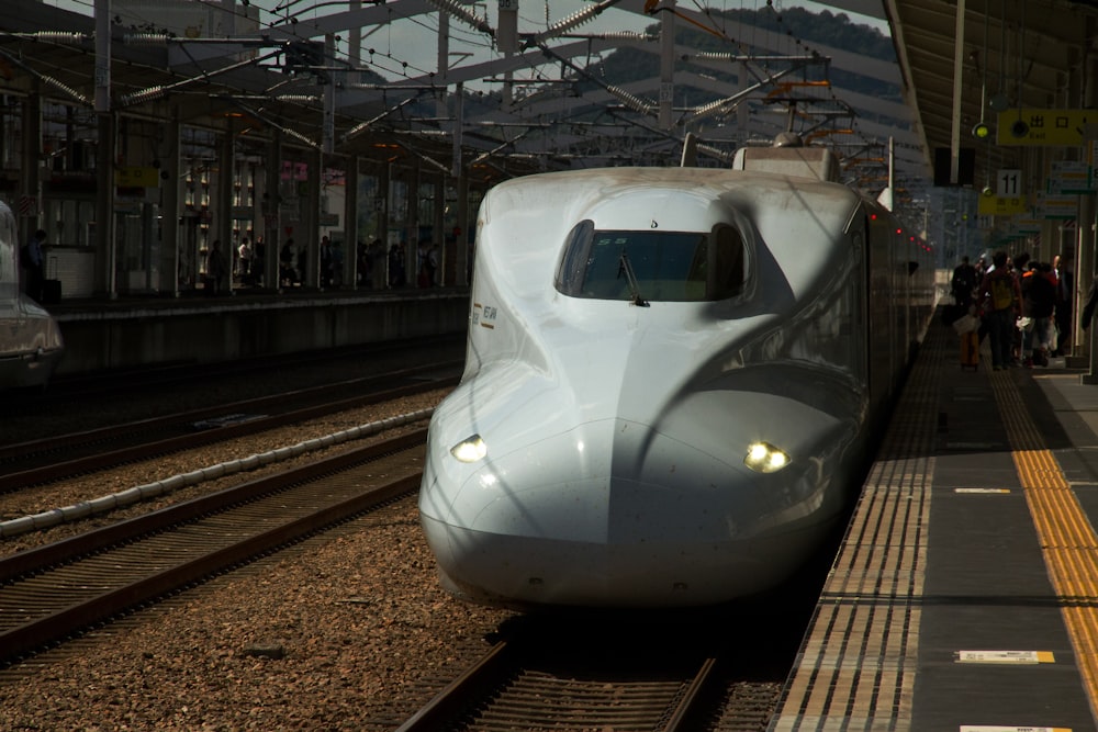 a white train traveling down train tracks next to a loading platform