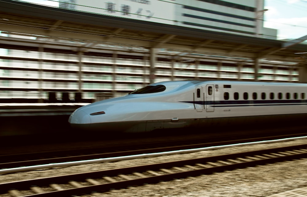 a white train traveling down train tracks next to a tall building