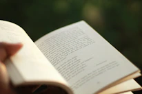 Close-up of hands holding the book with a soft golden background.