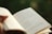A close-up of a person reading a book outdoors.