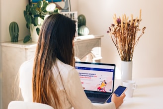Une femme qui travail sur un ordinateur et un téléphone et qui navigue sur le site web Booking.com