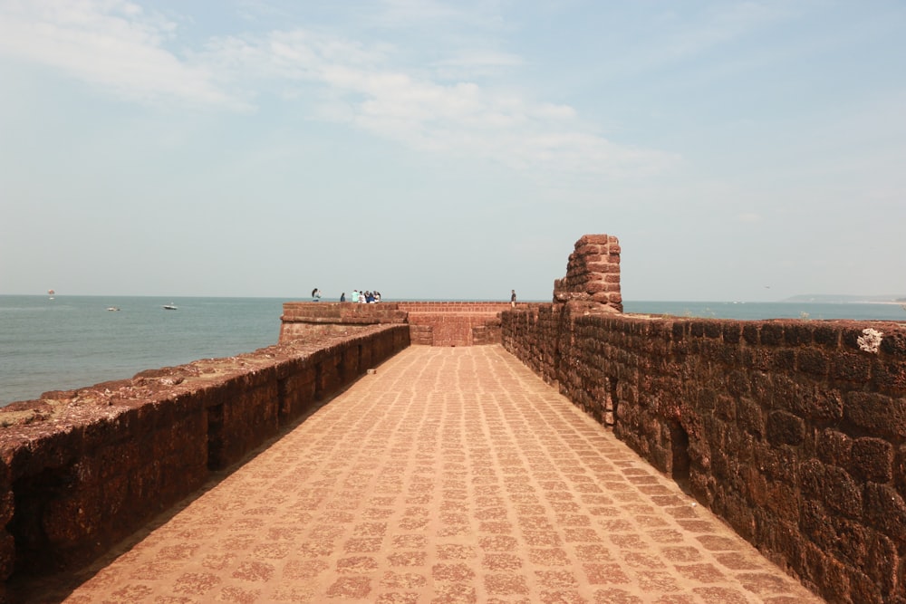 a brick walkway leading to the ocean on a sunny day