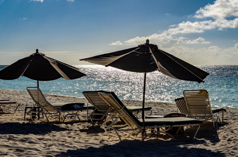 a couple of lawn chairs sitting on top of a sandy beach