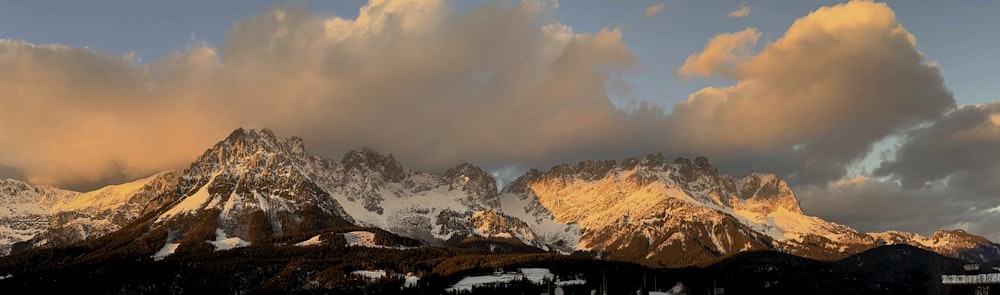 a snow covered mountain range under a cloudy sky