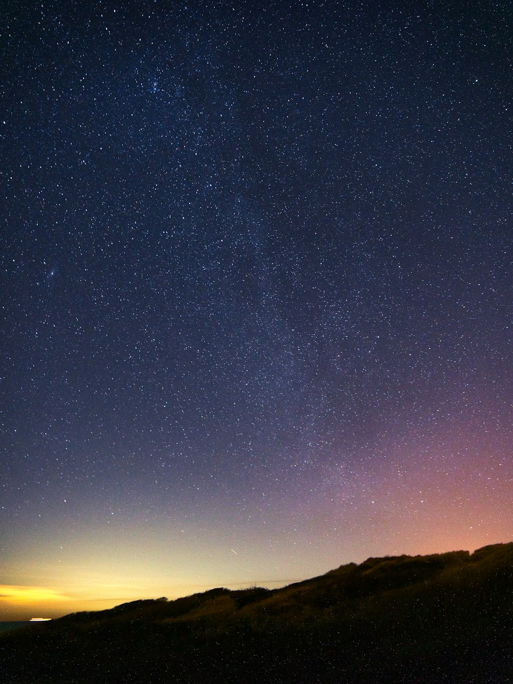 El cielo nocturno con estrellas sobre una colina