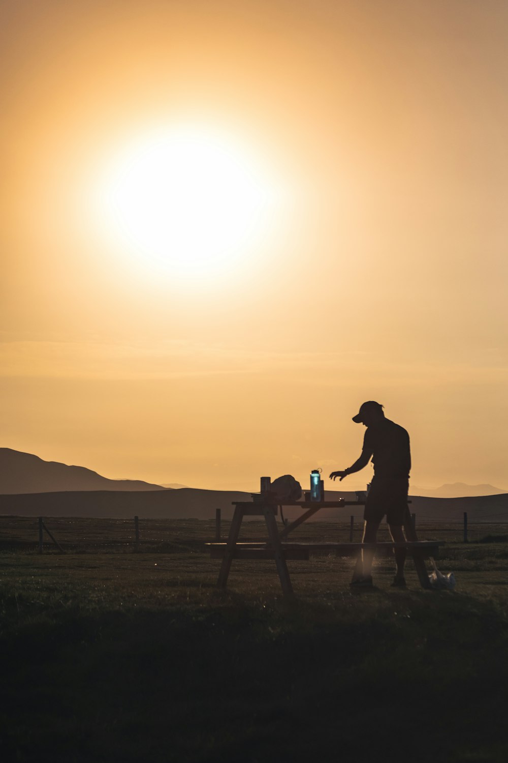 a man standing next to a picnic table in a field