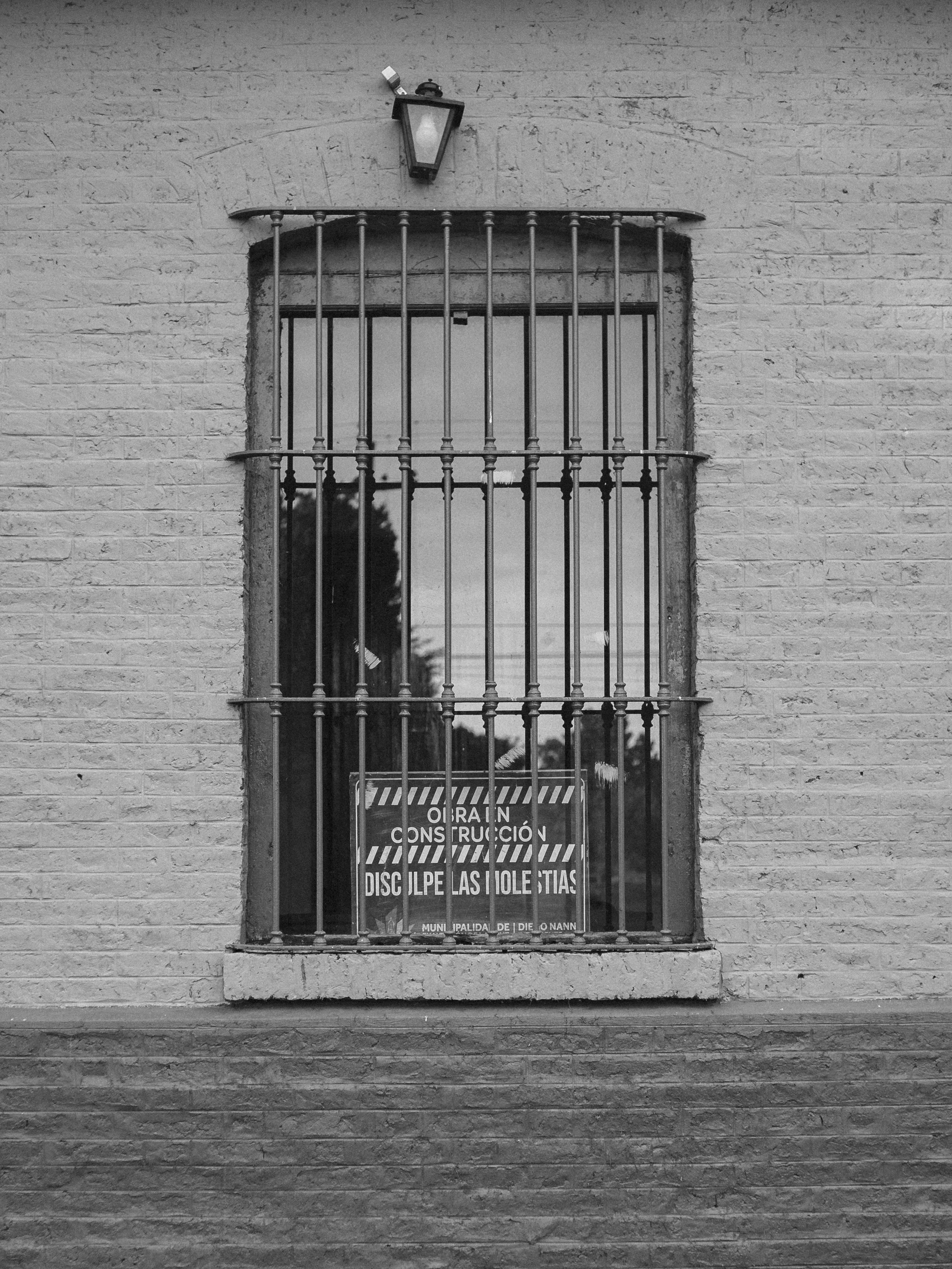 eine Ziegelmauer mit einem vergitterten Fenster und einem Schild darauf