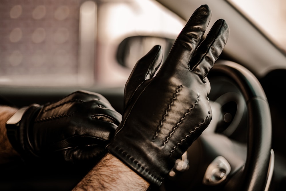 a man wearing black leather gloves driving a car