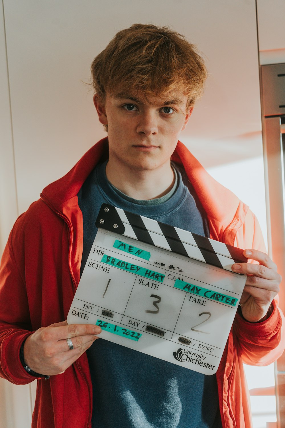 a young man holding a clapper board in his hands
