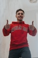 a man in a red sweatshirt giving a thumbs up
