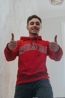 a man in a red sweatshirt giving a thumbs up