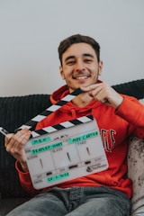 a man sitting on a couch holding a movie clapper