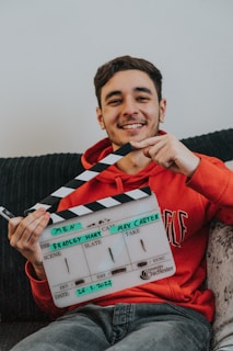 a man sitting on a couch holding a movie clapper