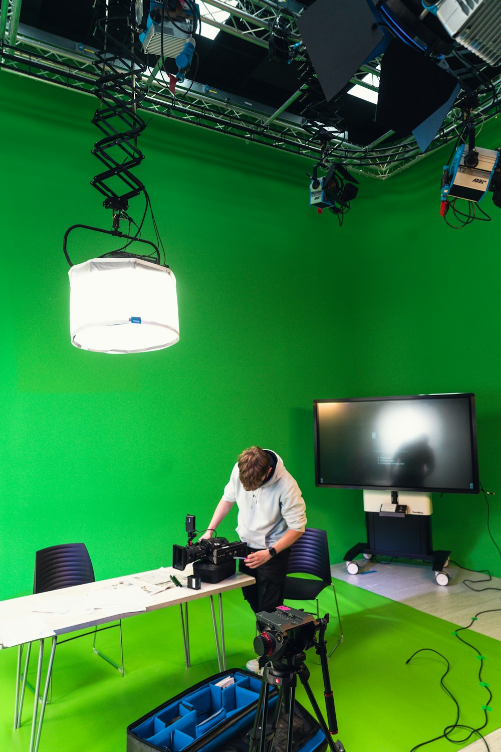 Ein Mann sitzt an einem Tisch vor einem Greenscreen