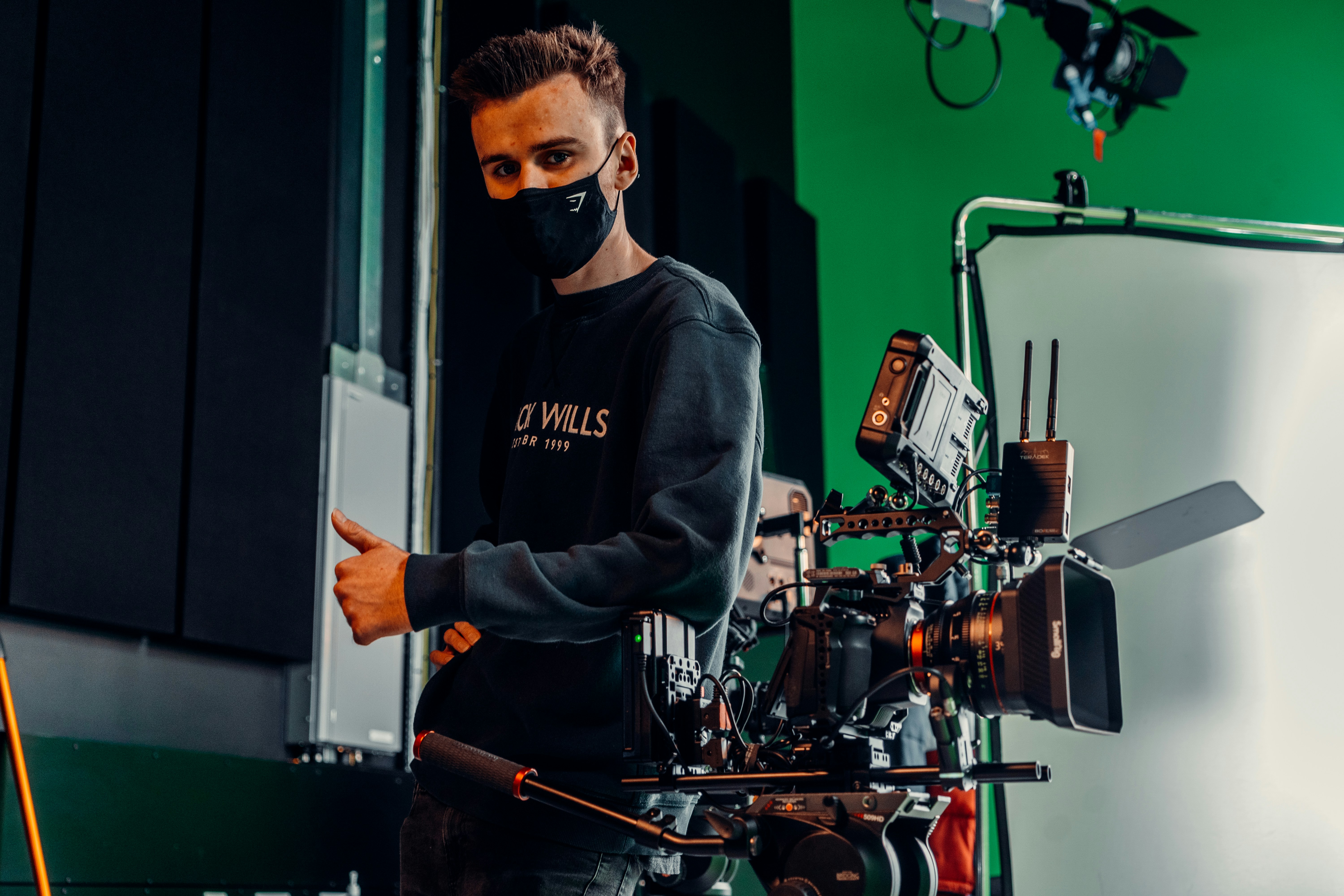 a man wearing a face mask standing in front of a camera