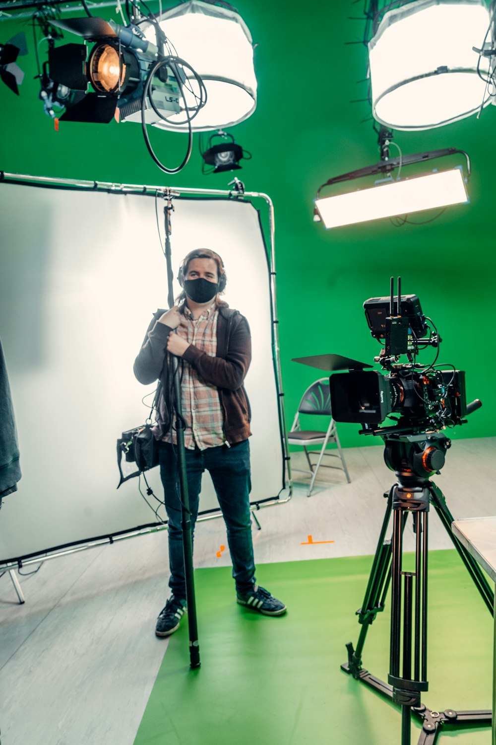 a man standing in front of a camera in a green room