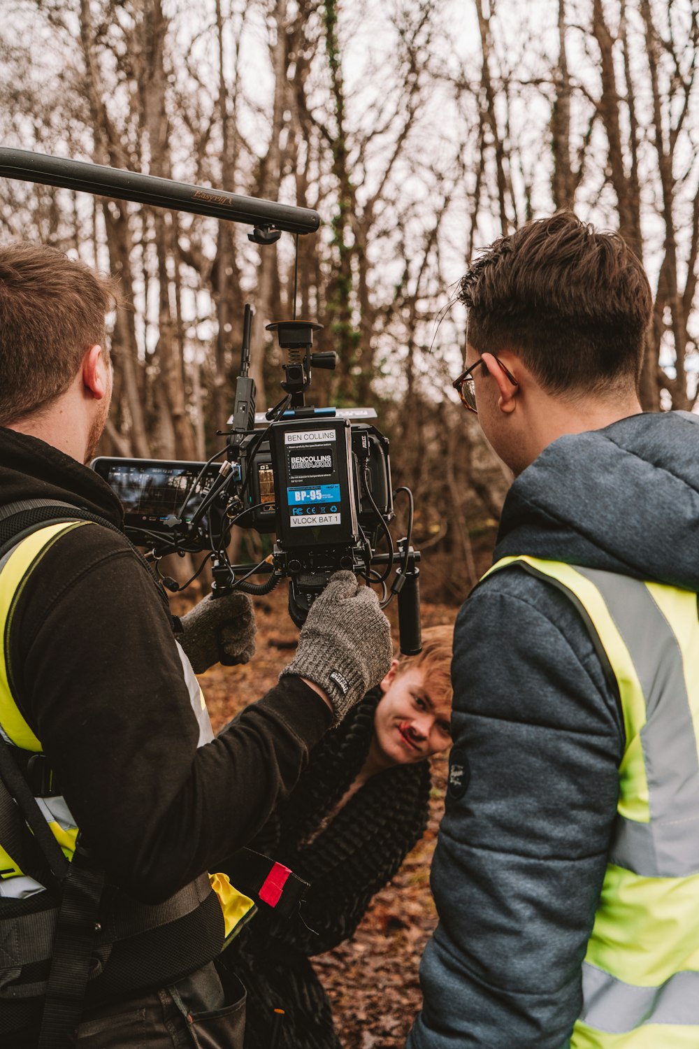 two men in vests standing in front of a camera