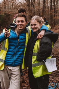 a man and a woman standing next to each other in the woods