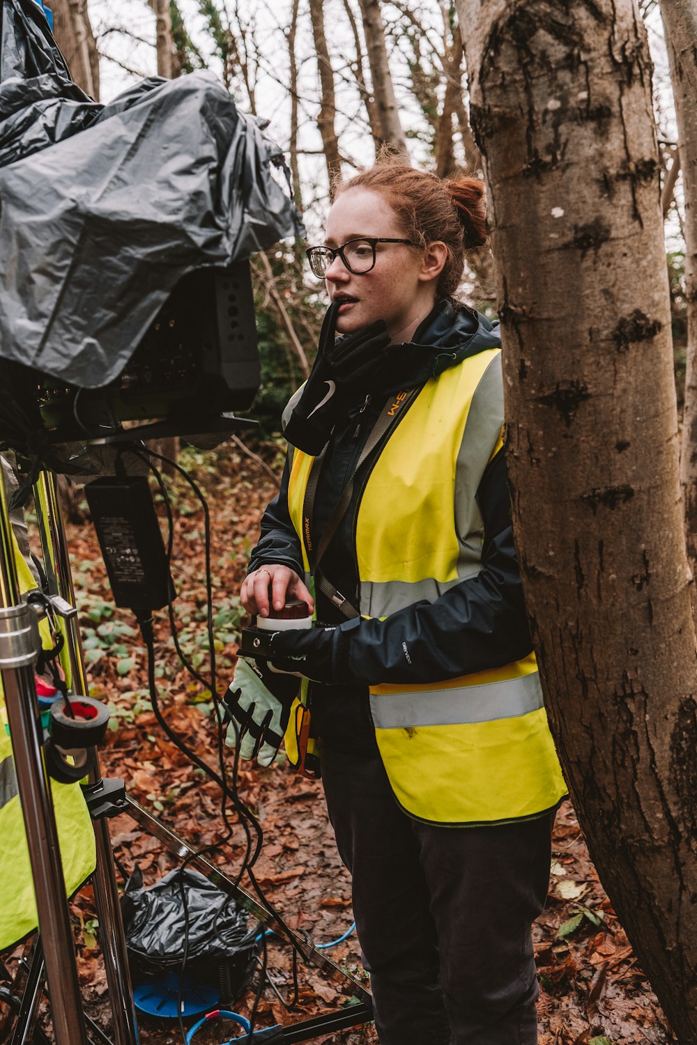 a woman in a yellow vest standing next to a tree