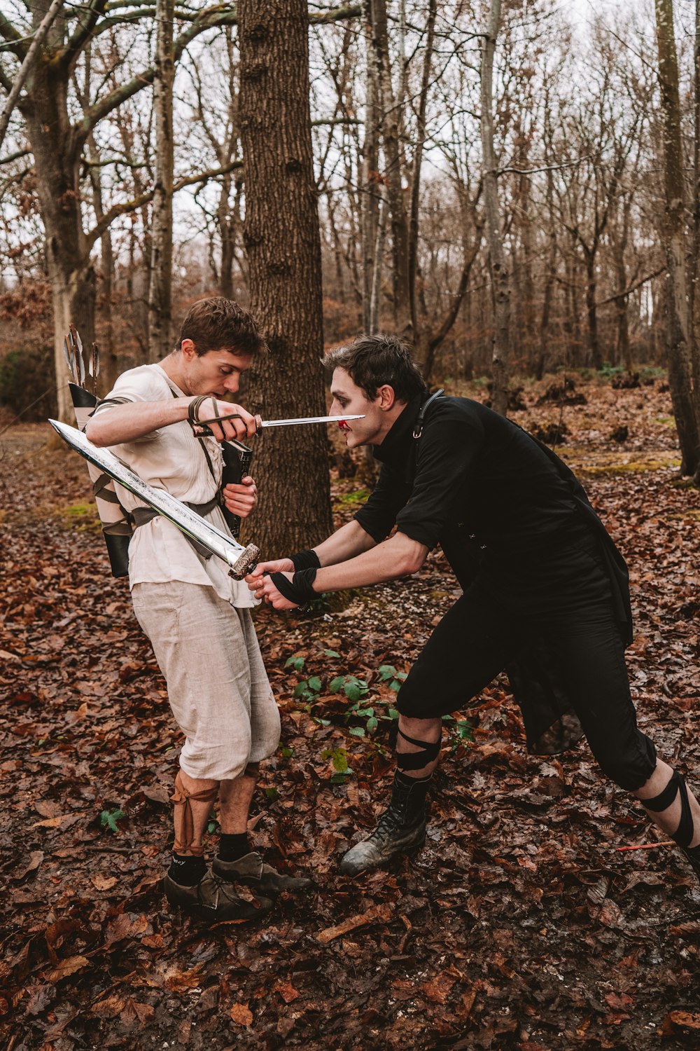 two men in the woods with swords in their hands