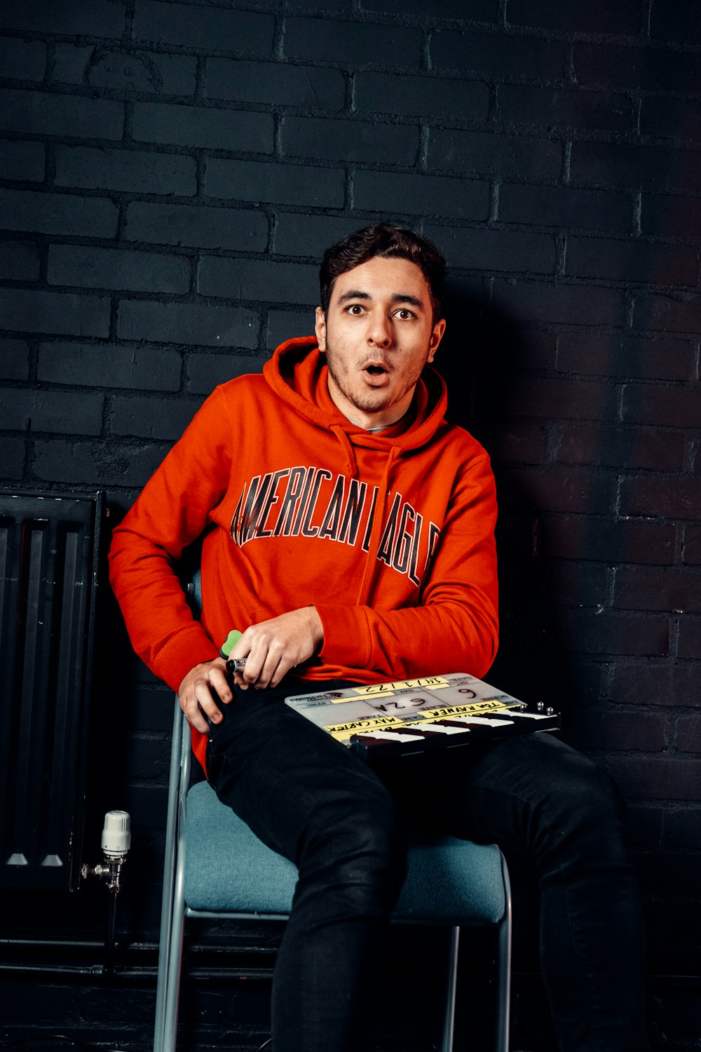 a man sitting on a chair in front of a brick wall