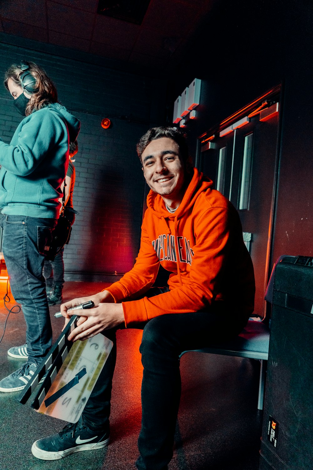 a man in an orange hoodie sitting on a bench