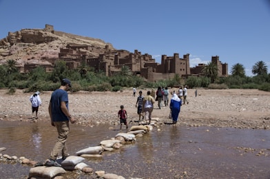 a group of people walking across a river