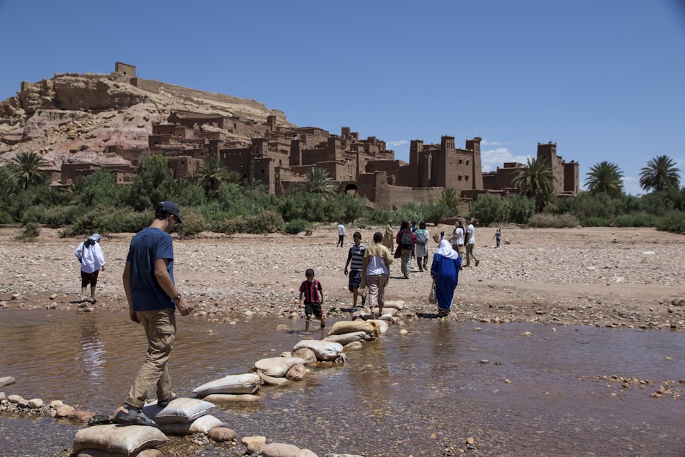 a group of people walking across a river