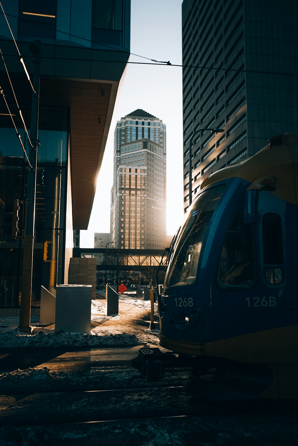 a blue and yellow train traveling past tall buildings