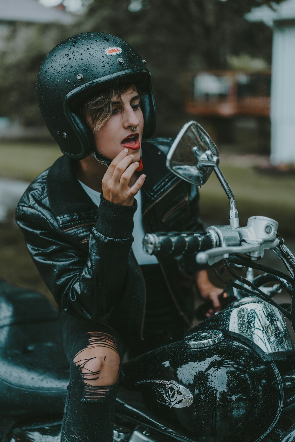 a boy in a leather jacket and helmet sitting on a motorcycle