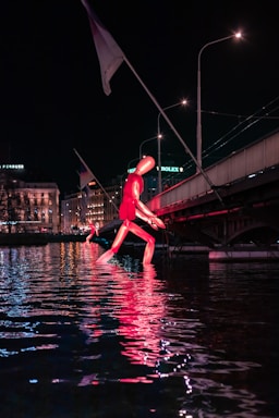a man in a red shirt jumping into a body of water