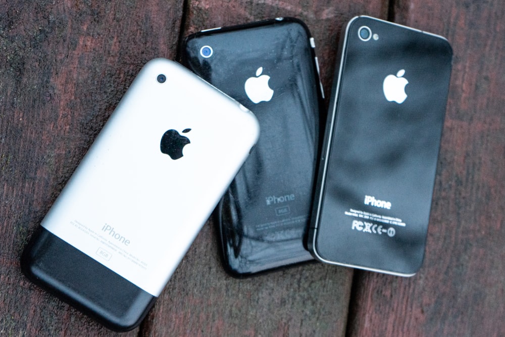 two iphones sitting next to each other on a wooden surface