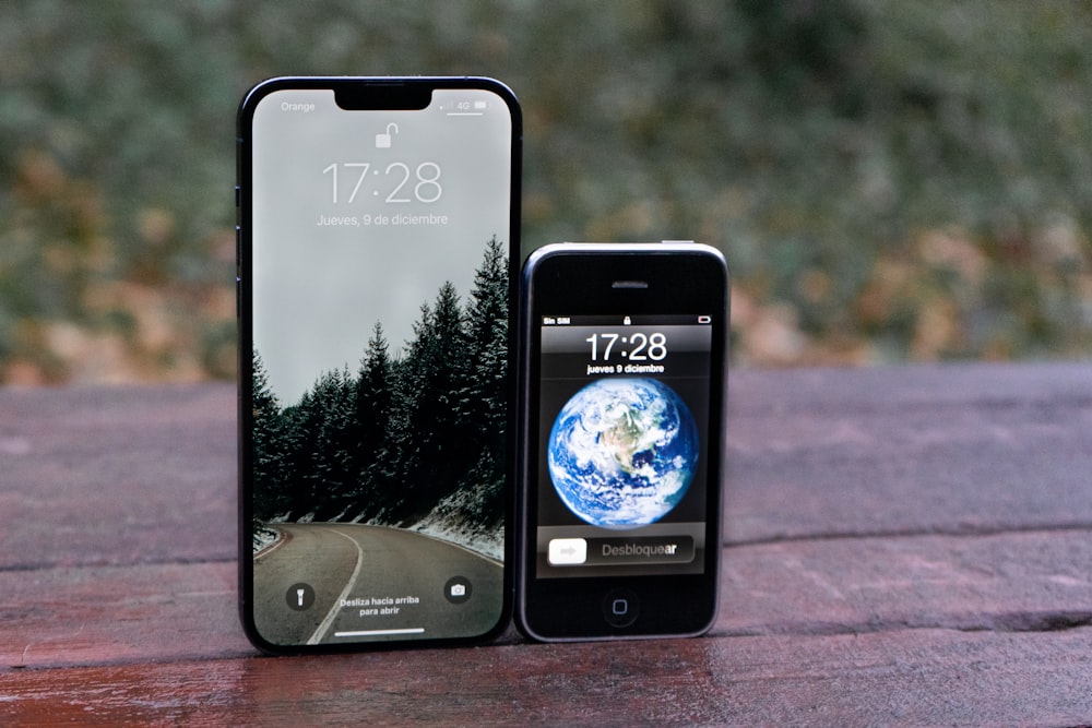 a cell phone sitting next to an iphone on top of a wooden table