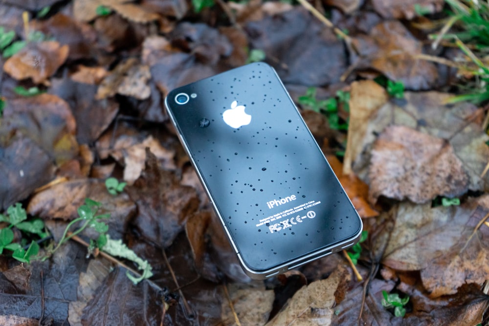 a cell phone laying on top of a pile of leaves