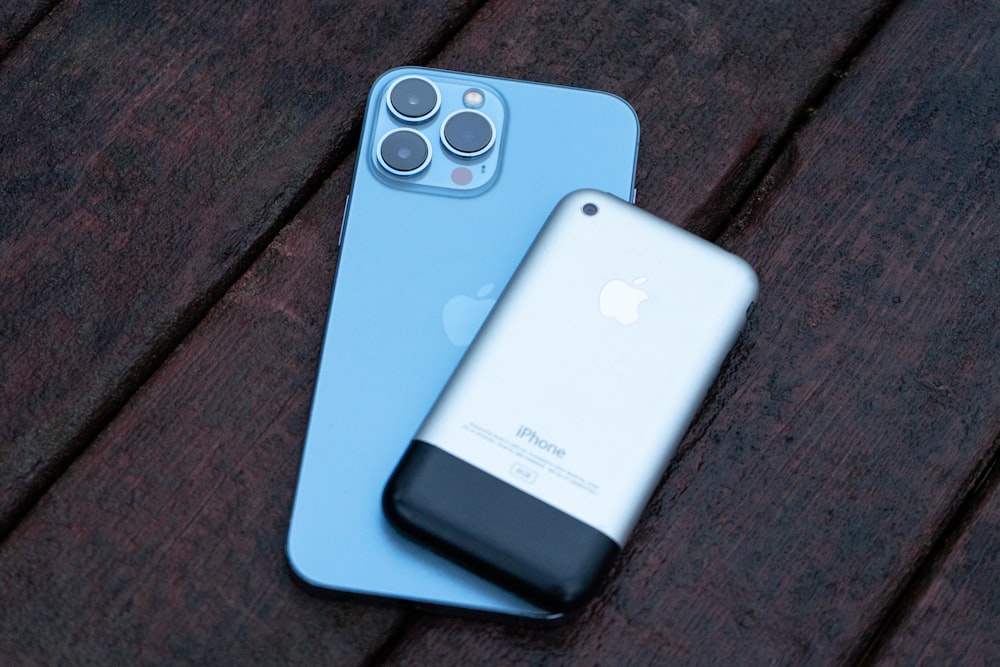 two iphones sitting next to each other on a wooden surface