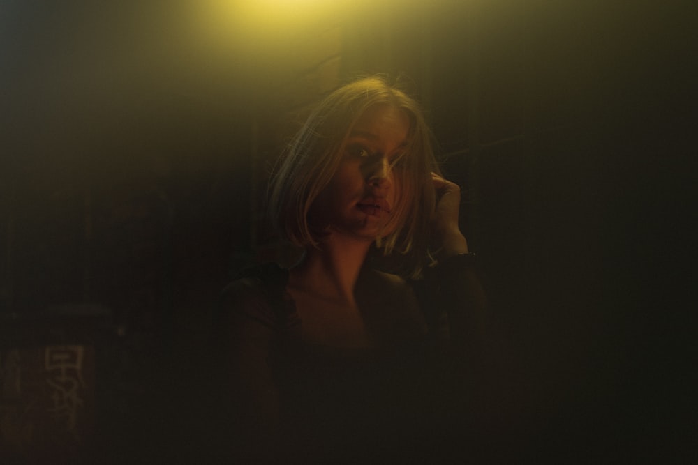 a woman standing in a dark room talking on a cell phone