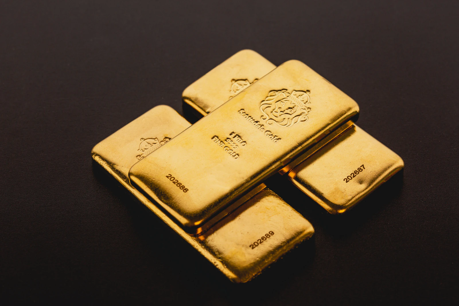 Three investment-grade gold bars arranged on a dark surface