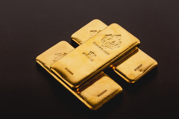 Four gold kilobars stacked on a dark surface