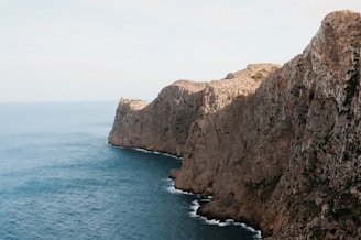 a rocky cliff with a body of water in the foreground