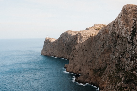 a rocky cliff with a body of water in the foreground