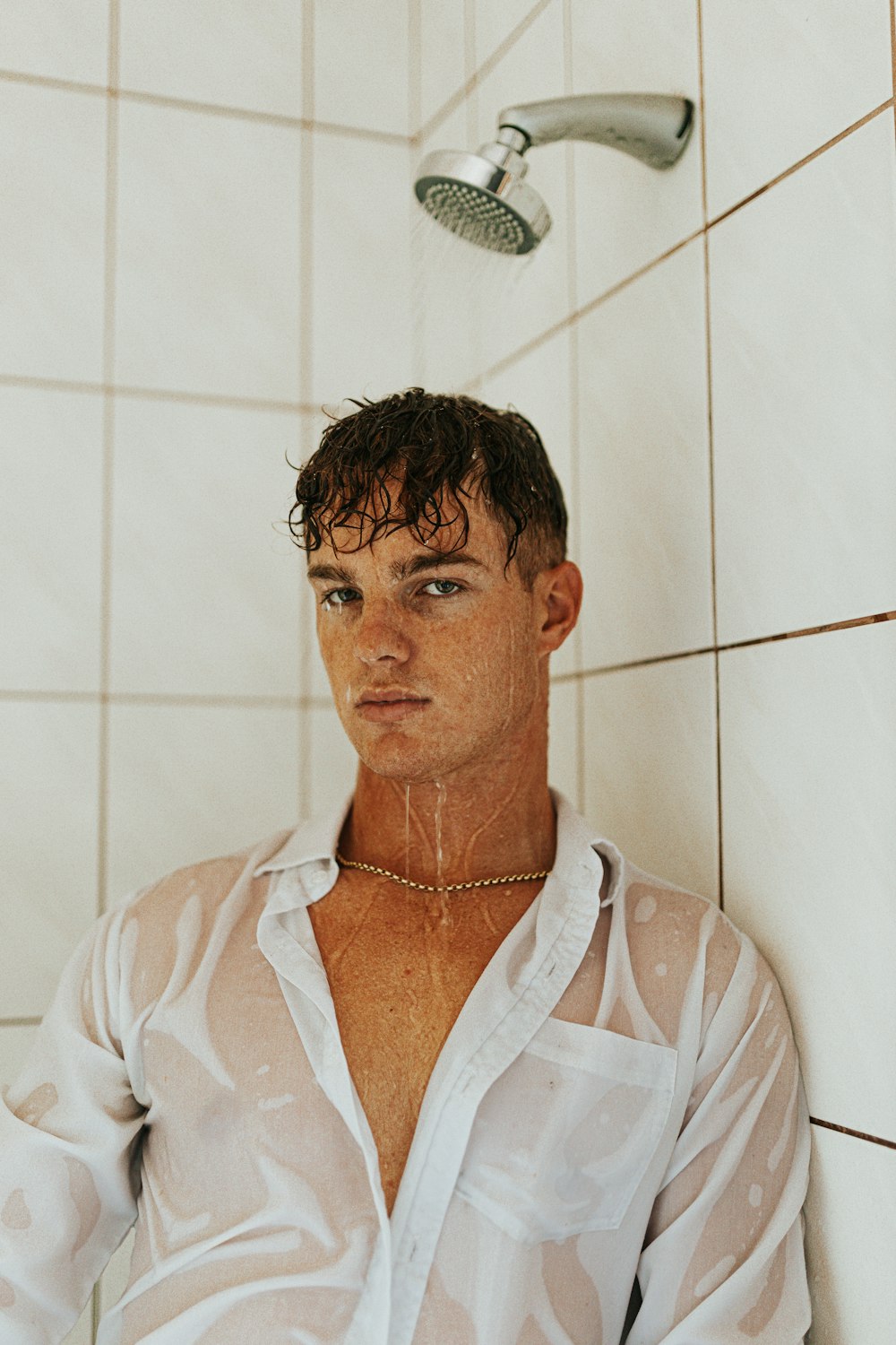 a man in a white shirt sitting in a shower