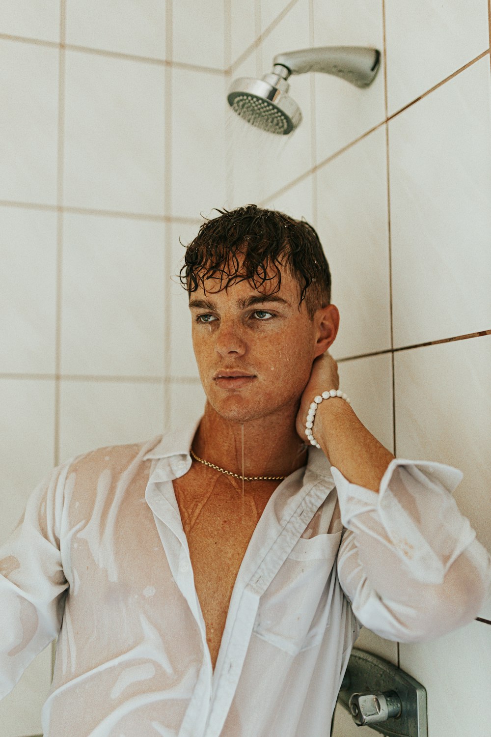 a man in a white shirt standing in a shower