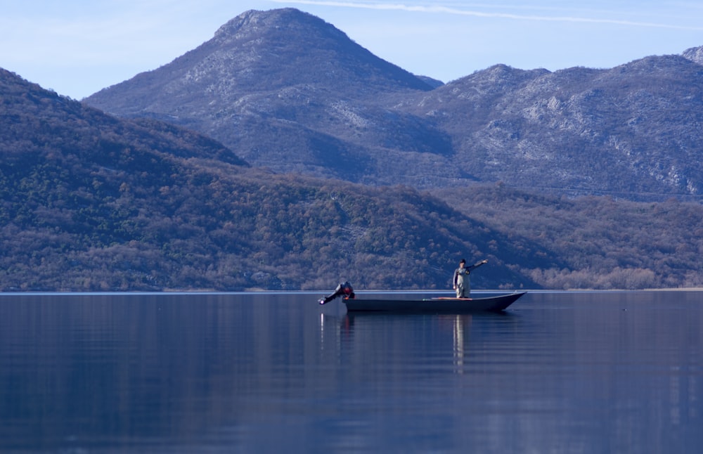 Un homme dans un bateau sur un lac avec des montagnes en arrière-plan