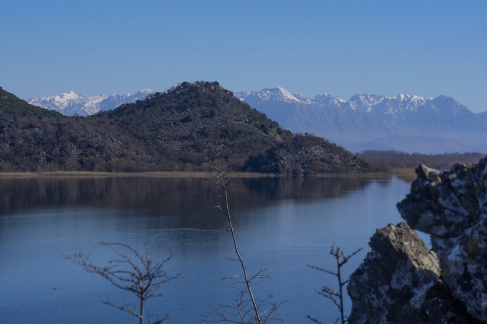 a lake surrounded by mountains with snow on the tops