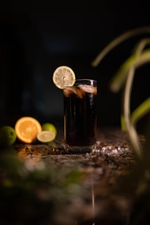 a glass of soda with a slice of lemon on the side