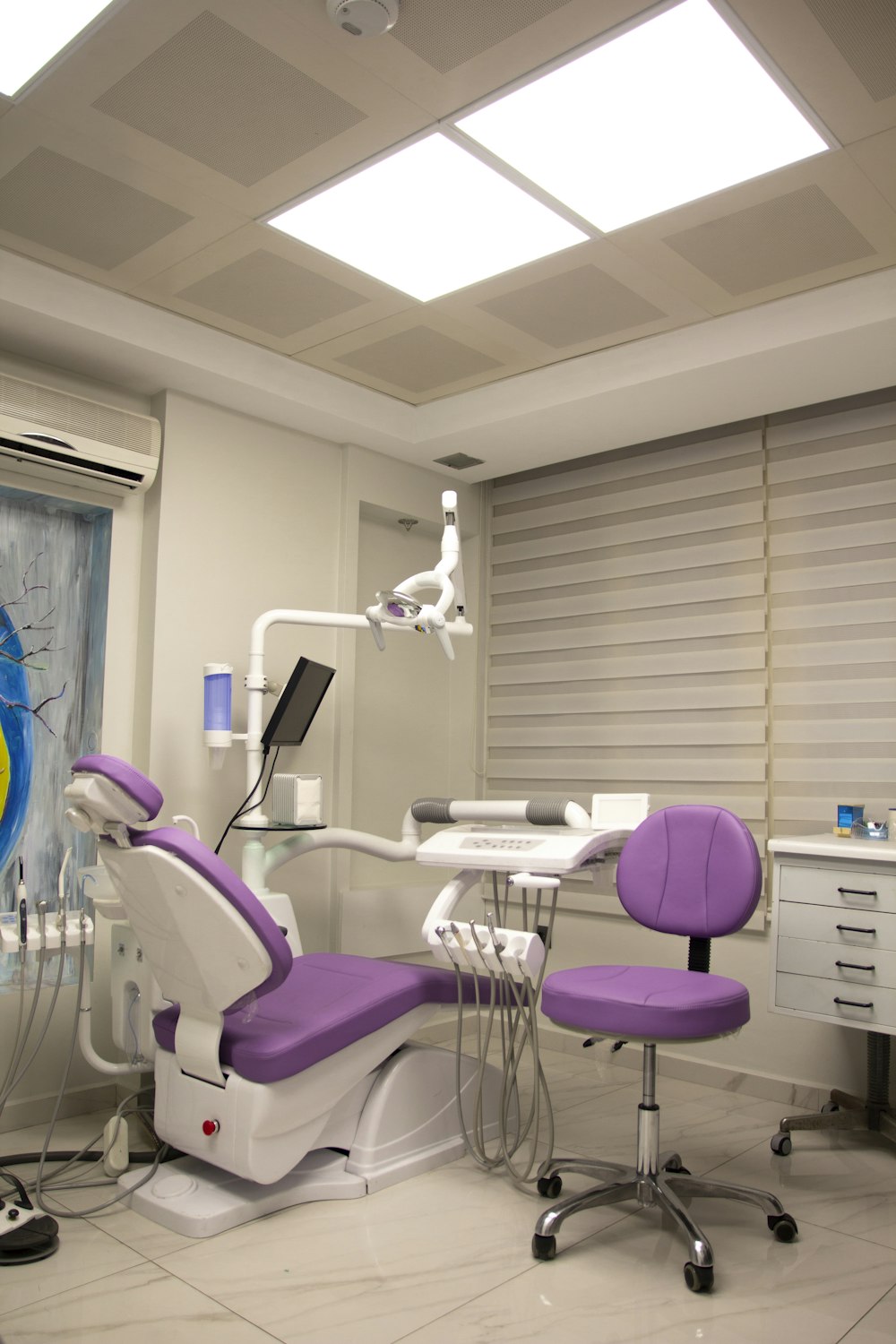 a dental room with a purple chair and a white desk