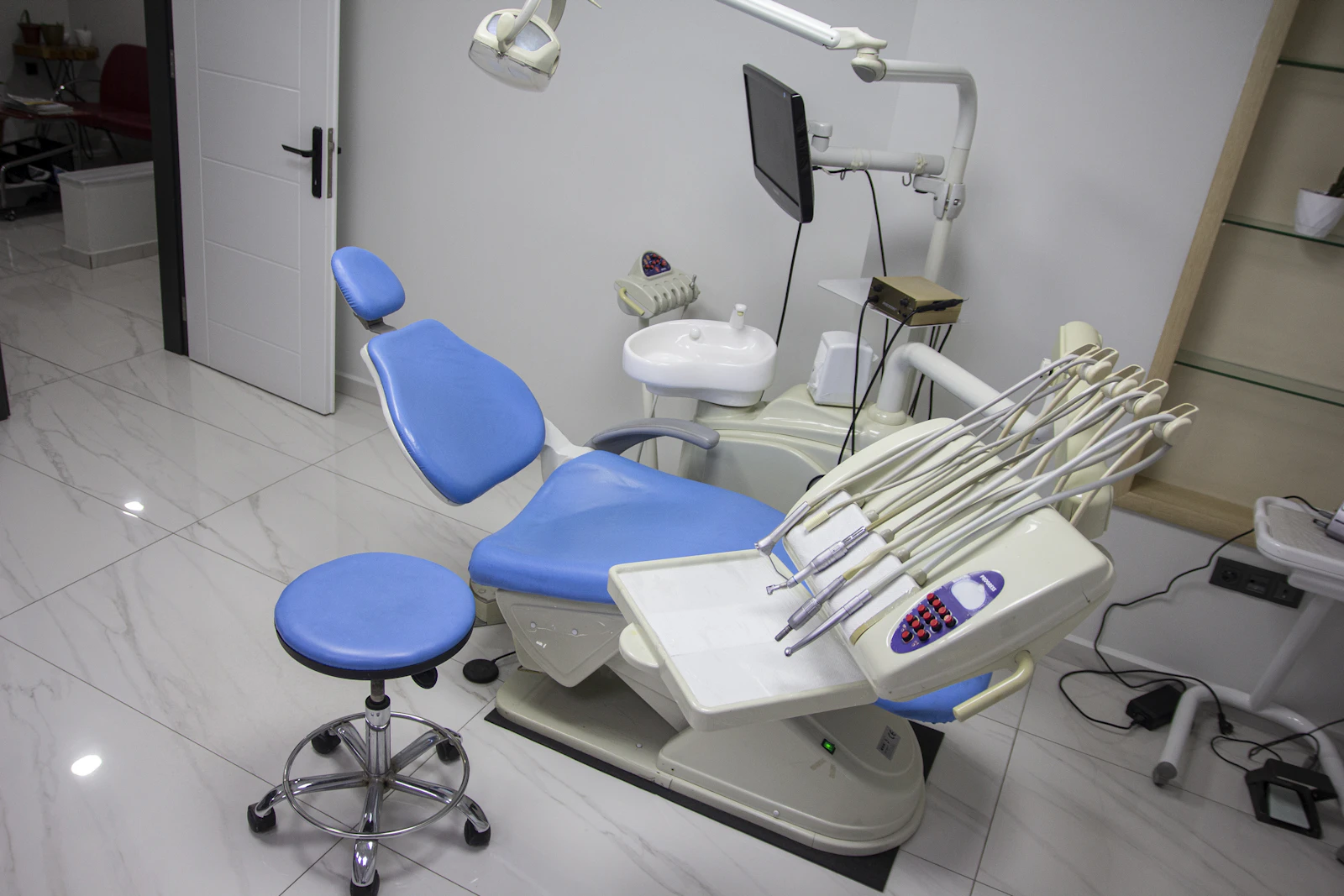 Modern dental treatment room with a blue chair and equipment.