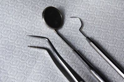 Dental instruments including mirrors and probes, set on a clean white surface.