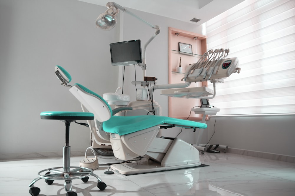 uma sala odontológica com uma cadeira e um monitor