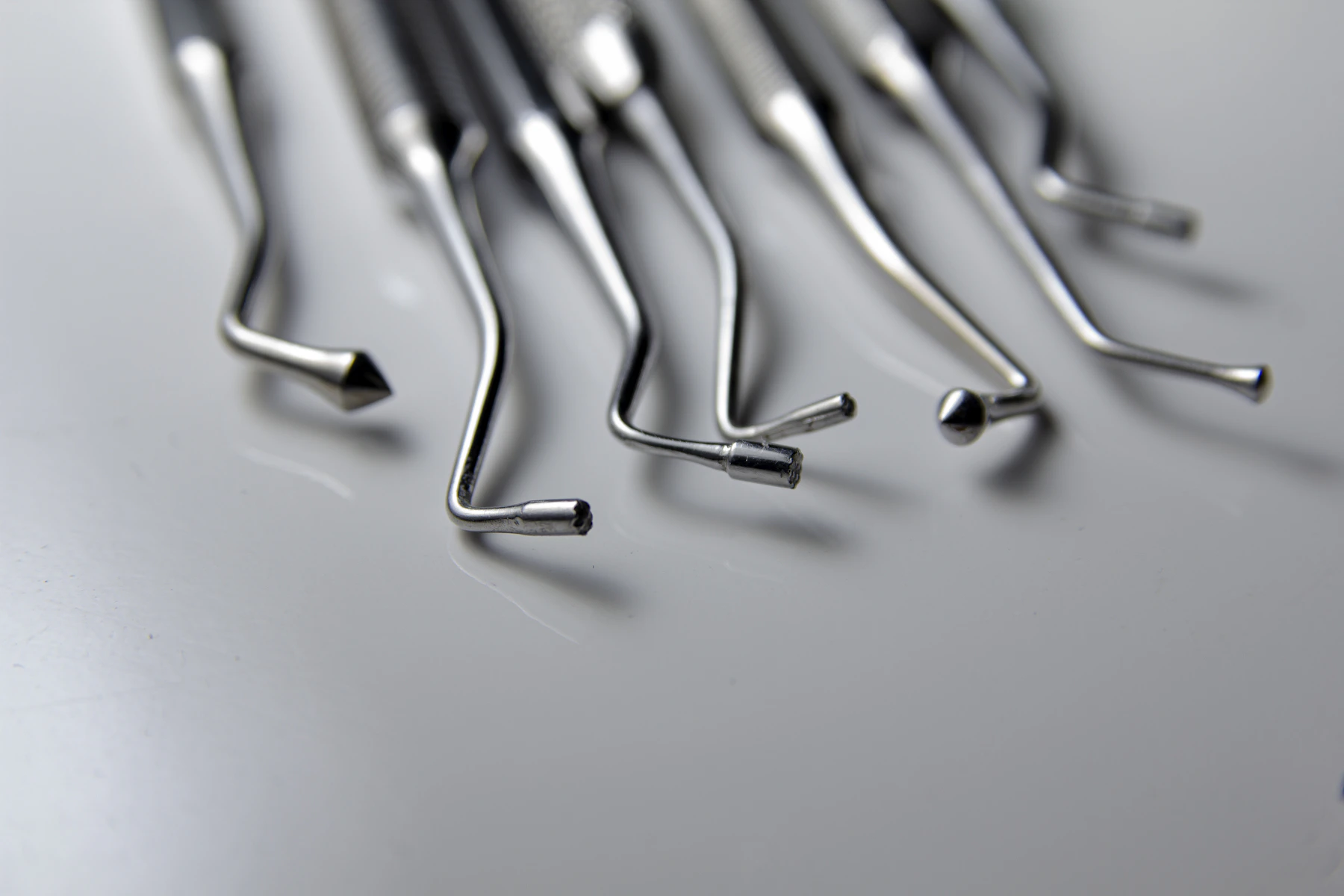 Instrumental dental de precisión — sondas y curetas odontológicas sobre superficie neutra · Consciencia Odontológica, Villa Nueva, Guaymallén, Mendoza